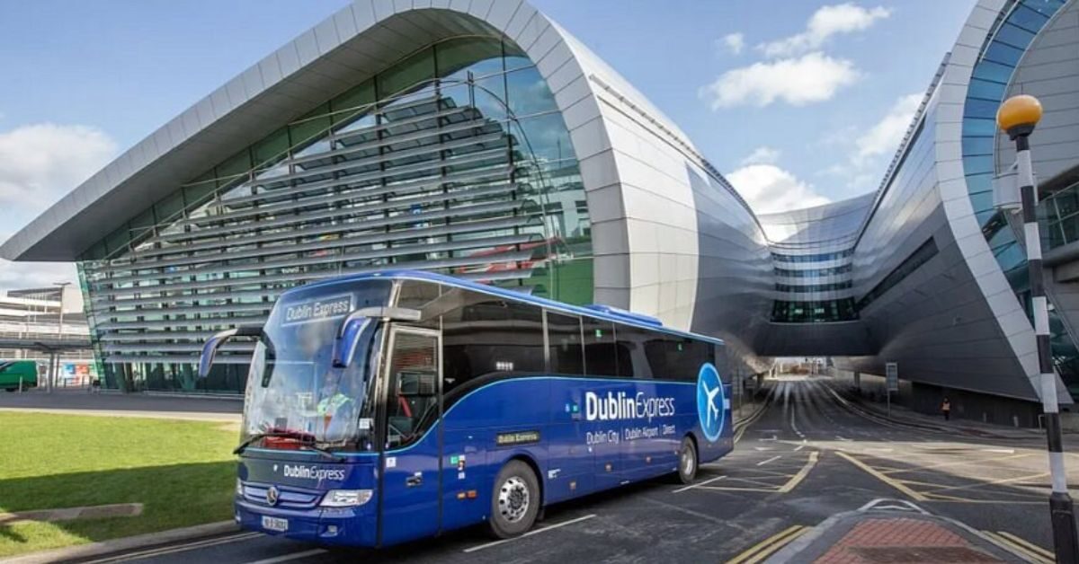 Dublin Express shuttle bus at modern airport terminal with sleek, curved architecture. Convenient city and airport transport.