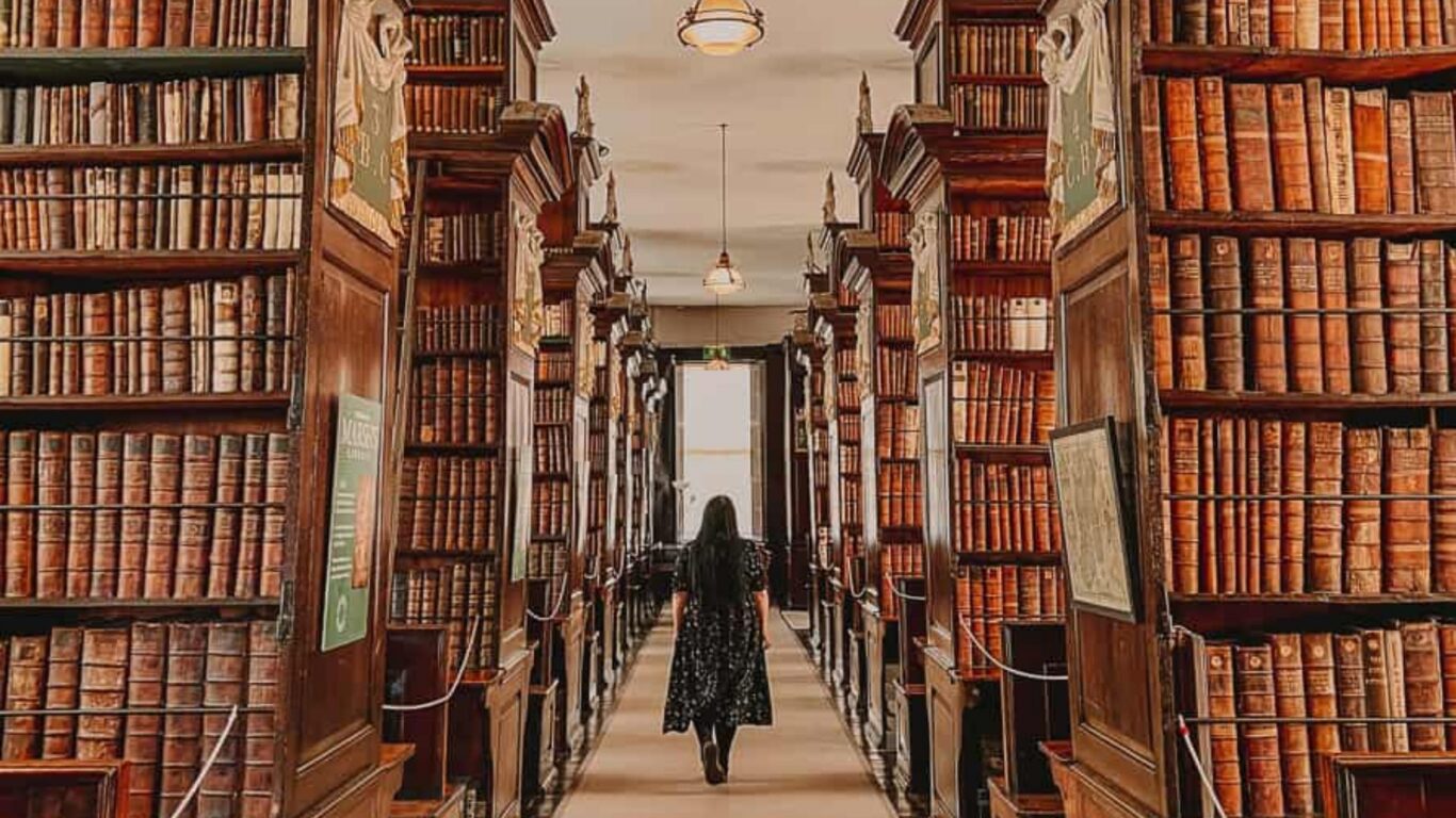 Explore a grand, historic library with soaring shelves of antique books and elegant wooden decor, perfect for book lovers.