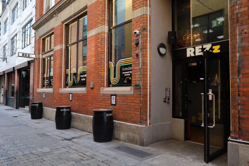 Street view of a brick building with large windows and a sign reading 