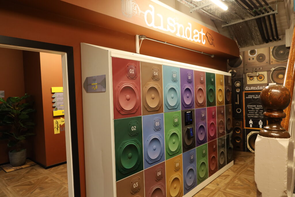 A wall of colorful numbered speaker lockers is displayed under a 