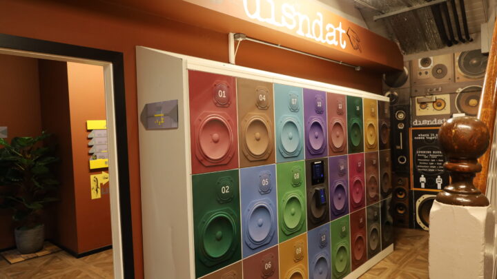 A wall of colorful numbered speaker lockers is displayed under a